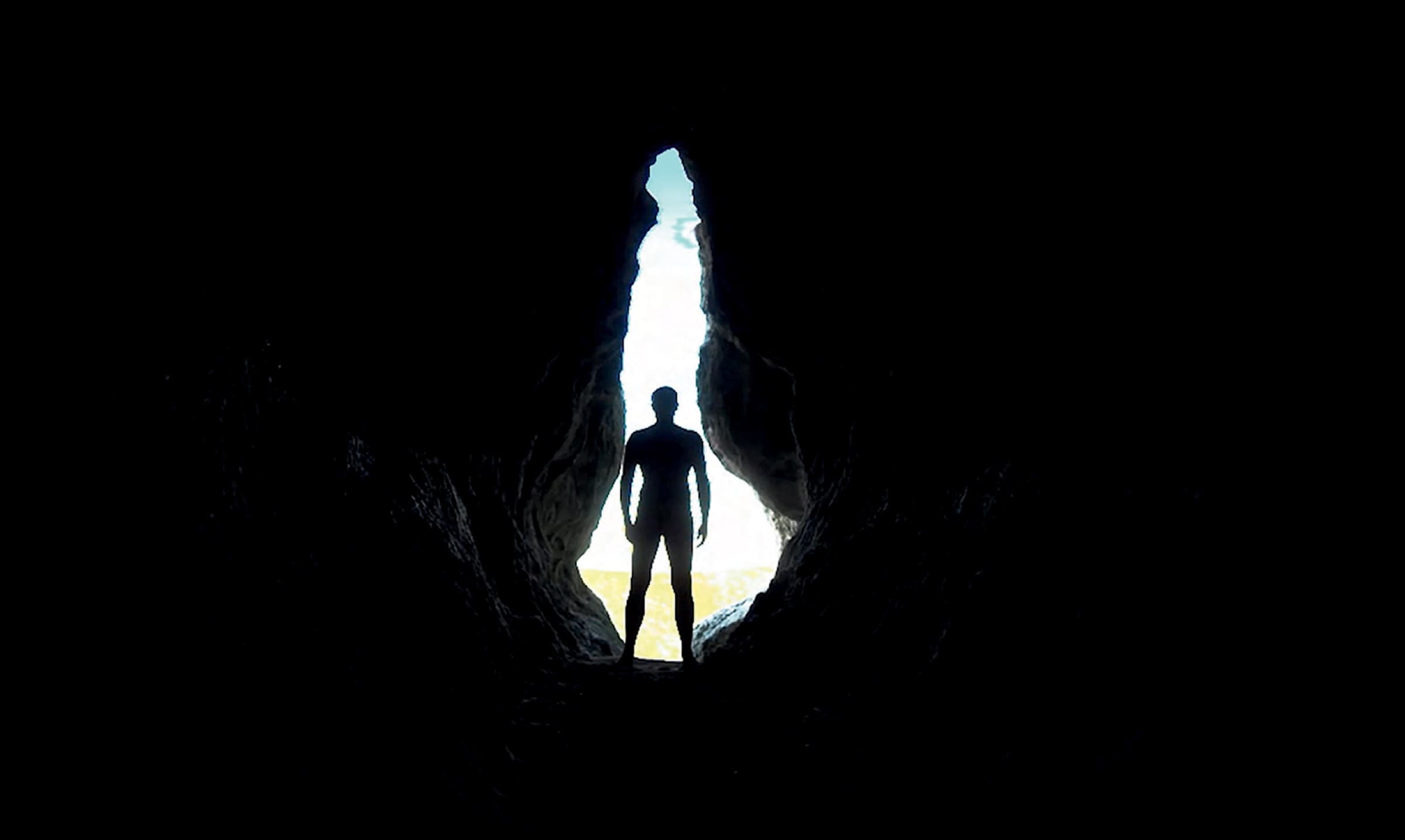 Figure silhouetted at a cave opening