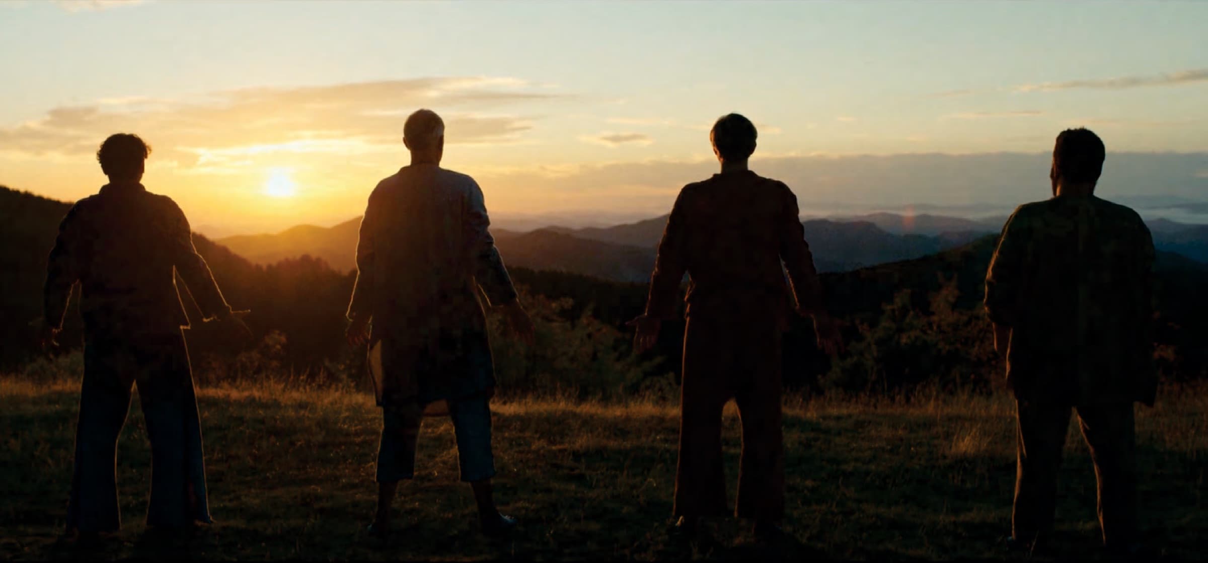Four disciples silhouetted against a mountain sunset